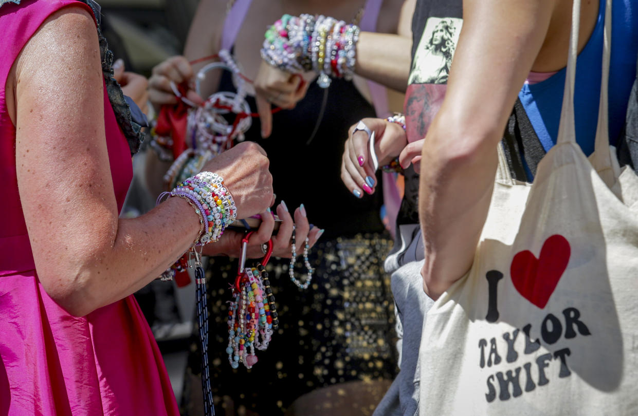 Several people's arms in view draped in multiple bracelets.