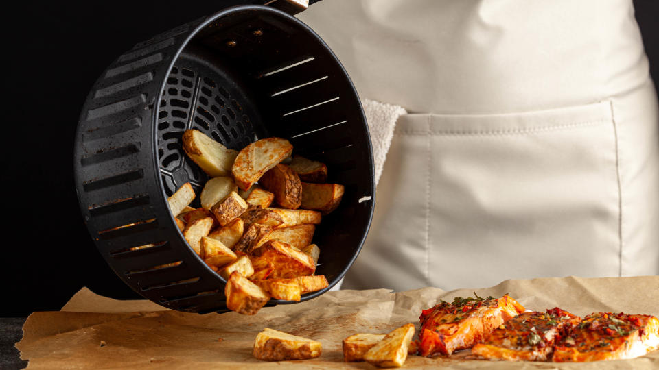 An air fryer basket emptying out potato wedges