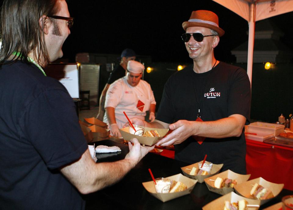 Chef Andrew Carmellini shares his Dutch Burger while competing in the Burger Bash at the Food Network South Beach Wine & Food Festival in Miami Beach, Fla., Friday Feb. 24, 2012. (AP photo/Jeffrey M. Boan)