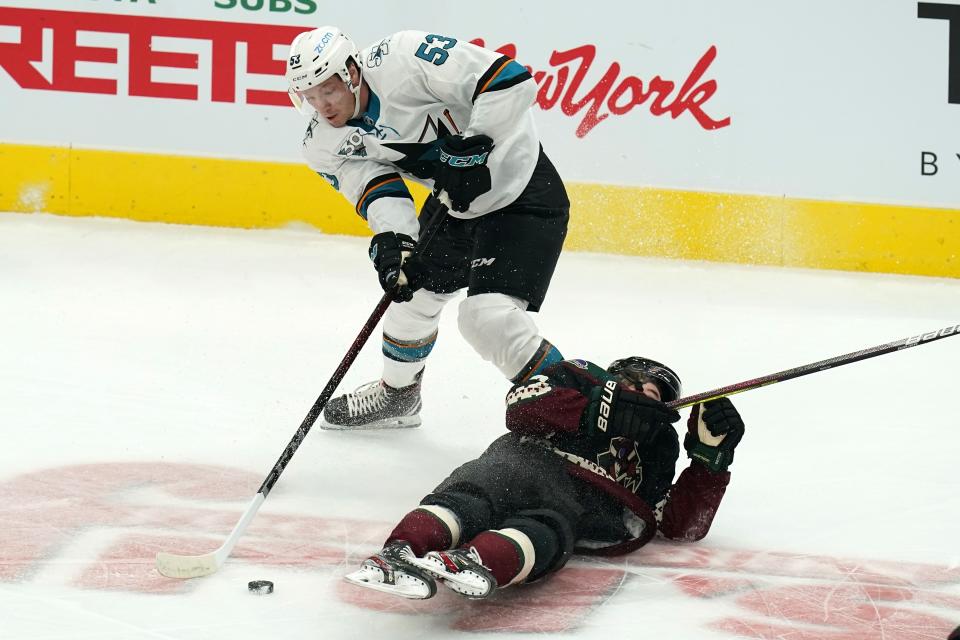San Jose Sharks defenseman Nicolas Meloche (53) gets the puck after sending Arizona Coyotes right wing Clayton Keller, right, to the ice during the first period of an NHL hockey game Thursday, Jan. 14, 2021, in Glendale, Ariz. (AP Photo/Ross D. Franklin)