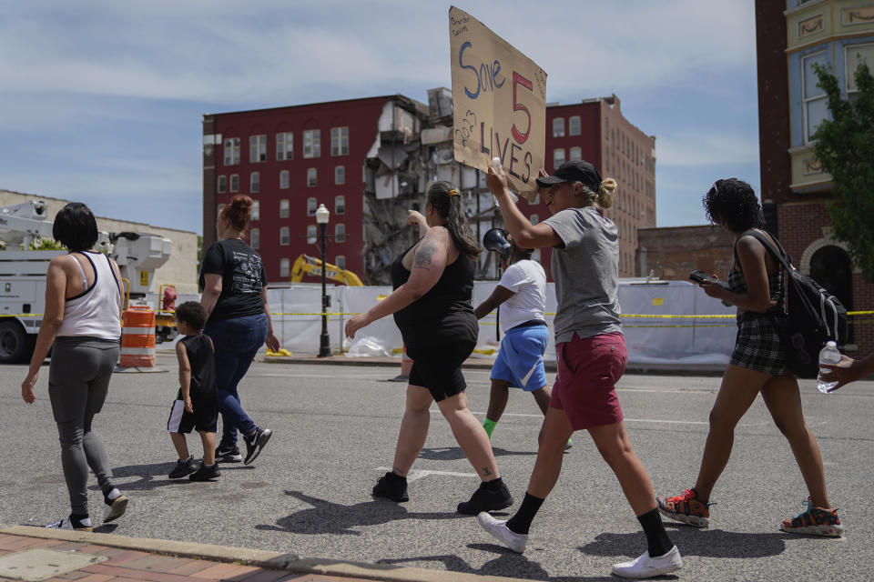 Protesters march in the street at the scene where on Sunday an apartment building partially collapsed in Davenport, Iowa, Wednesday, May 31, 2023. Five residents of a six-story apartment building that partially collapsed in eastern Iowa remained unaccounted for Tuesday, and authorities feared at least two of them might be stuck inside rubble that was too dangerous to search. (AP Photo/Erin Hooley)