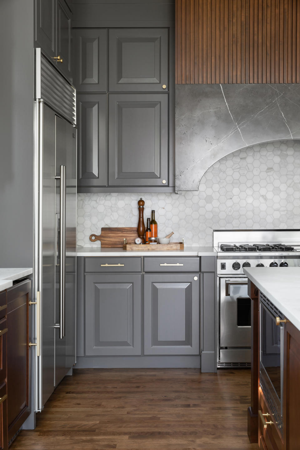 A steel range with wooden cabinets, flooring and quartz countertop