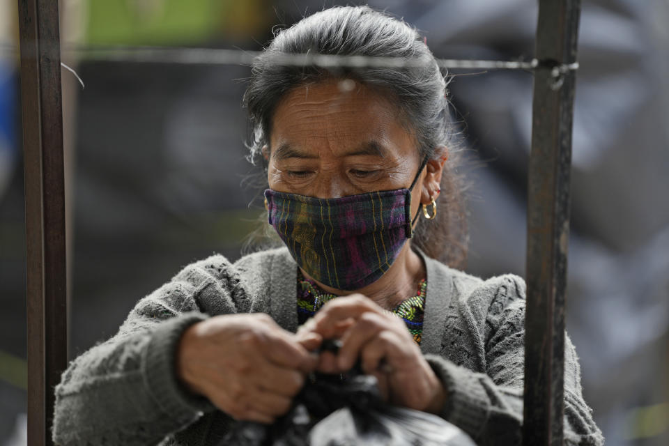 A vendor removes merchandise from her stall at the market, closed on the second day of a four-day lockdown decreed by local authorities to help curb the spread of COVID-19 in the Kaqchikel Indigenous town of San Martin Jilotepeque, Guatemala, Friday, July 9, 2021. On Thursday, Guatemala announced its highest number of infections since the pandemic began, with 3,000 infected in a single day. (AP Photo/Moises Castillo)