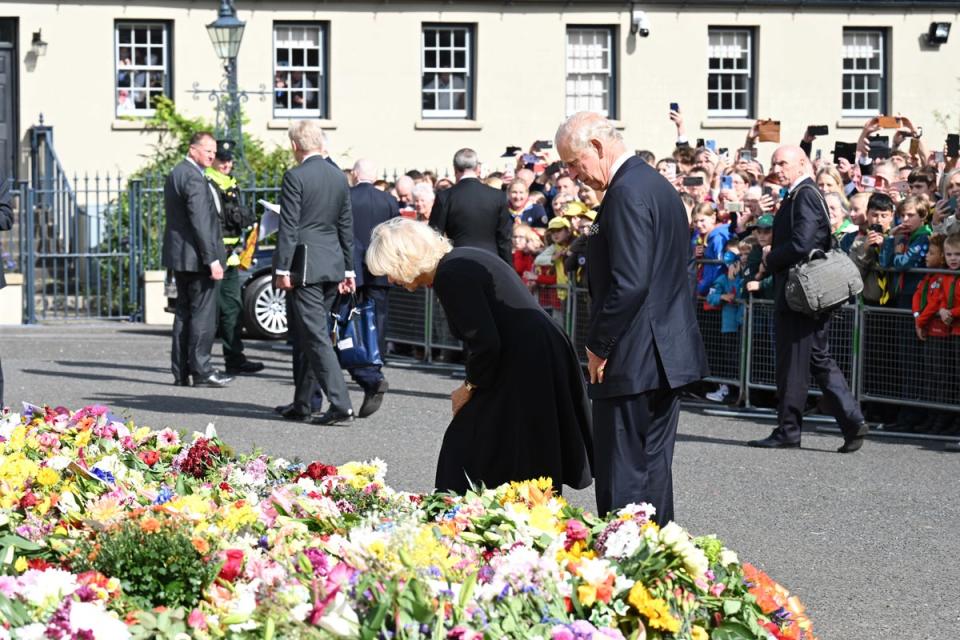 Charles and the Queen Consort look at floral tributes as they arrive at Hillsborough Castle (Michael Cooper/PA) (PA Wire)