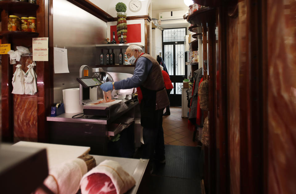 In this photo taken on Thursday, March 12, 2020, a shopkeeper works in a deli meat and cold cuts shop in Codogno, Italy. The northern Italian town that recorded Italy’s first coronavirus infection has offered a virtuous example to fellow Italians, now facing an unprecedented nationwide lockdown, that by staying home, trends can reverse. Infections of the new virus have not stopped in Codogno, which still has registered the most of any of the 10 Lombardy towns Italy’s original red zone, but they have slowed. For most people, the new coronavirus causes only mild or moderate symptoms. For some it can cause more severe illness. (AP Photo/Antonio Calanni)