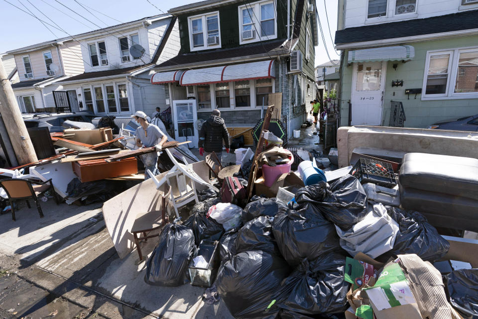 FILE - In this Sept. 3, 2021 file photo, people clear debris and damaged belongings from their homes in the Queens borough of New York. Floodwaters from the remnants of Hurricane Ida have long receded but Northeast residents still in the throes of recovery are being hit with another unexpected blow: Thousands of families without flood insurance are now swamped with financial losses after runoff from the fierce storm submerged basements, cracked foundations and destroyed valuable belongings. (AP Photo/Mark Lennihan, File)