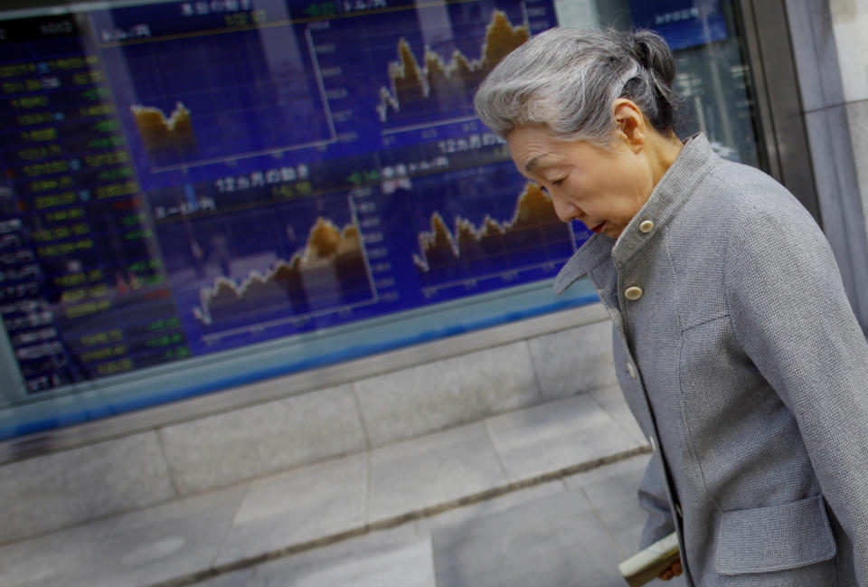 A woman walks by a securities firm in Tokyo, Wednesday, March 12, 2014. Asian stock markets sank Wednesday as recent falls in Chinese copper and iron prices added to jitters that the world's No. 2 economy is continuing to slow. (AP Photo/Junji Kurokawa)