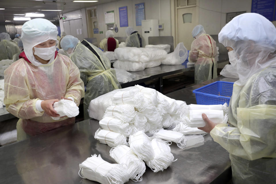 Workers package medical masks in a factory in Nantong in eastern China's Jiangsu Province, Monday, Jan. 27, 2020. China on Monday expanded sweeping efforts to contain a viral disease by extending the Lunar New Year holiday to keep the public at home and avoid spreading infection. (Chinatopix via AP)