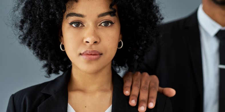 shot of a young businesswoman with her coworker’s hand on her shoulder