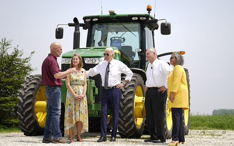 President Biden stands with 4 people in front of a tractor
