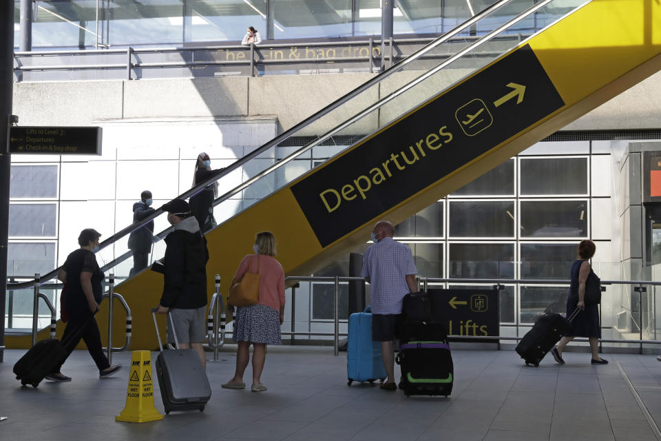 Passengers head to Departures, at the North Terminal of Gatwick Airport near Crawley, just south of London, Wednesday, July 22, 2020. With all schools now closed, Friday would normally be the busiest departure day of the year for London’s Gatwick Airport with families heading off to the sun-soaked beaches in southern Europe. Not this year as the coronavirus pandemic has meant many have opted against making their annual summer migration to countries like Spain and Greece. Gatwick would in any normal year be expecting to fly some 85,000 holidaymakers on Friday alone. It expects less than 10,000 passenger departures on Friday. (AP Photo/Matt Dunham)