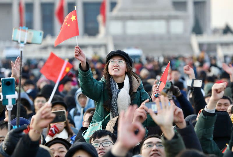 People wave Chinese national flags as they gather for a flag-raising ceremony to mark the New Year at the Tiananmen Square in Beijing