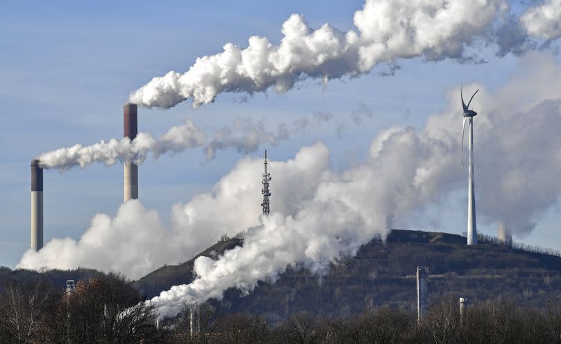 A Uniper coal-fired power plant and BP refinery steam beside a wind generator in Gelsenkirchen, Germany.