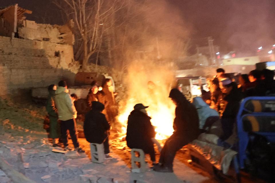 Residents keep warm around a fire in the early morning after an earthquake in Dahejia, Jishishan County, in northwest China’s Gansu province (AFP via Getty Images)