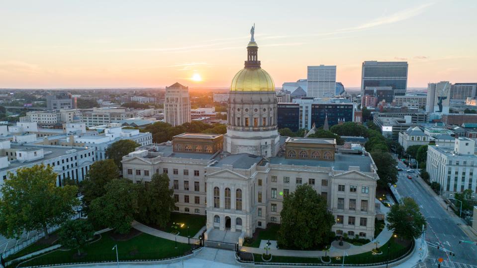 The sun sets behind the gold dome of the Georgia State Capitol in Atlanta, Sunday, Aug. 28, 2022. (AP Photo/Steve Helber)