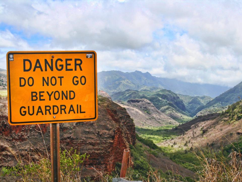 A sign near Waimea Canyon in the Hawaiian island of Kauai, Hawaii, warns hikers not to go beyond the guardrail.