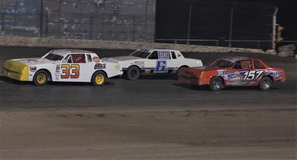 Jason Duggins, driving the 33 car, leads Ryan Greenwood in the 6 car and Mylee JoAnn (157) into the turn during an IMCA hobby stock race, Saturday, April 16, 2022 at Aztec Speedway.
