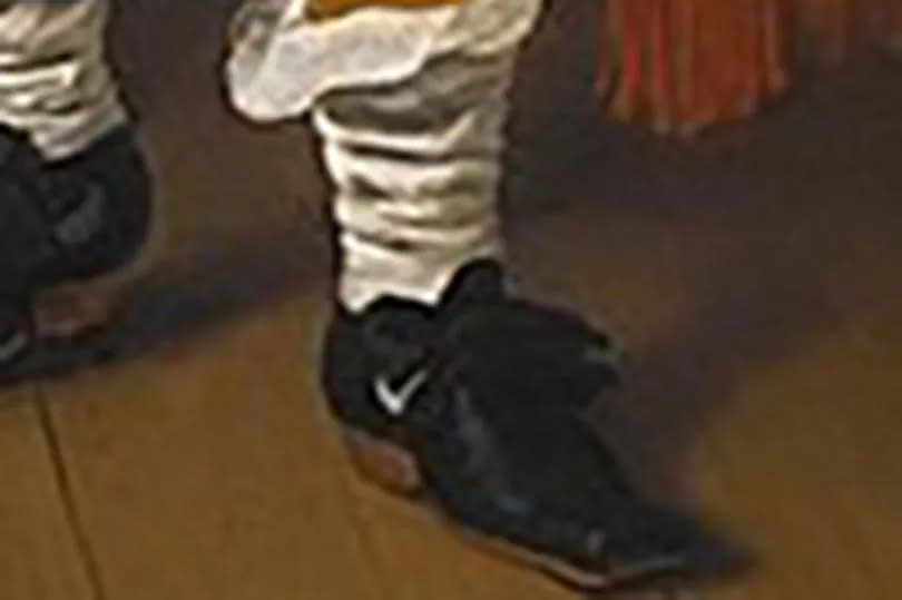 The boy's shoes have a swoosh-like white mark