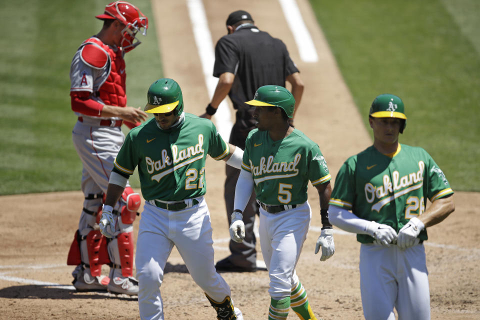 Oakland Athletics' Tony Kemp (5) is congratulated by Ramon Laureano (22) and Matt Olson, right, and Kemp scored on a sacrifice fly by Laureano during the third inning of the team's baseball game against the Los Angeles Angels on Monday, July 27, 2020, in Oakland, Calif. (AP Photo/Ben Margot)