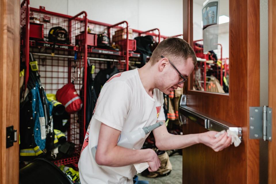 Jehred Bennett, 20, cleans crash bars and door handles as part of his janitorial duties at the New Philadelphia Fire Department fire station, where he works part time.