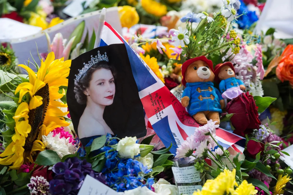 LONDON, UNITED KINGDOM - SEPTEMBER 11: A portrait of Queen Elizabeth II is placed next to Union Jack flag and Paddington bears among flowers as crowds of people visit a memorial site in Green Park on the third day of national mourning following the death of Queen Elizabeth II in London, United Kingdom on September 11, 2022. Queen Elizabeth II, Britain's longest reigning monarch, has died peacefully at the age of 96 at Balmoral Castle on Thursday after 70 years on the throne. (Photo by Wiktor Szymanowicz/Anadolu Agency via Getty Images)