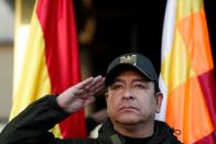 The Police Commander Vladimir Yuri Calderon salutes in front of the Wiphala and Bolivian flags during a ceremony at the General Command of the police in La Paz