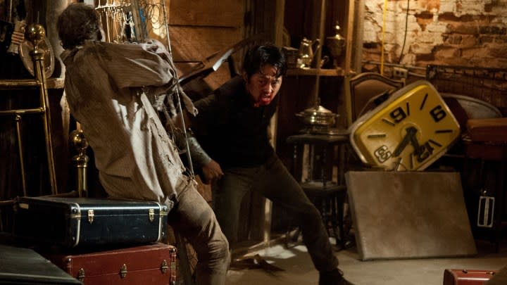 Glenn killing a walker with the leg of a chair while tied down in a scene from The Walking Dead.