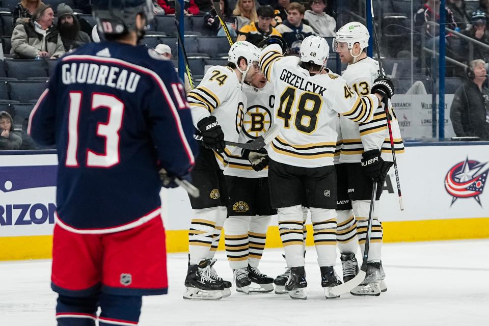 Jan 2, 2024; Columbus, Ohio, USA; Boston Bruins teammates celebrate a goal by defenseman Kevin Shattenkirk (12) in front of Columbus Blue Jackets left wing Johnny Gaudreau (13) during the second period of the NHL hockey game at Nationwide Arena.
