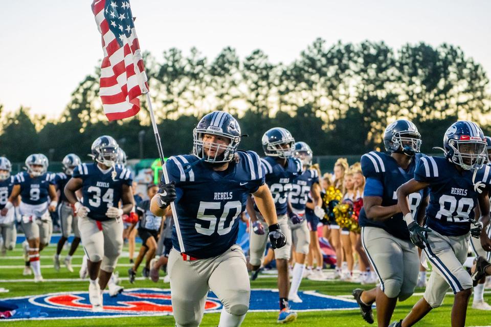 Effingham County's Samuel Jarriel carries the American flag as the Rebels storm the field before the start of a game this season.