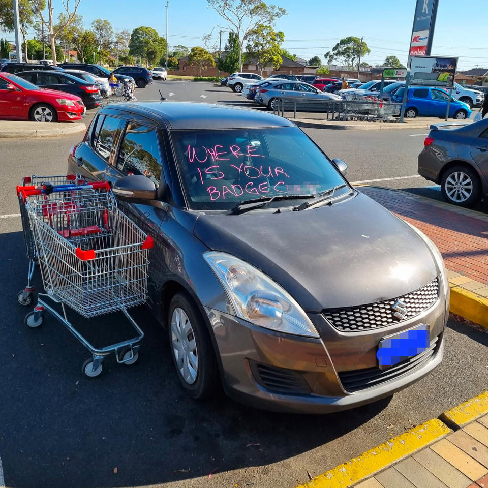 A grey Suzuki in a disabled parking bay with an abusive message in pink on the windscreen. . Source: Kyle Lemon/ Facebook