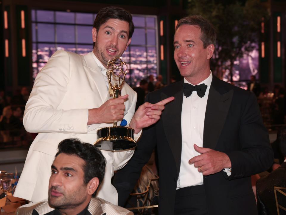 nicholas braun points at matthew macfadyen while holding an emmy, pointing gleefully at macfadyen. kumail nanjiani can be seen in the bottom left corner