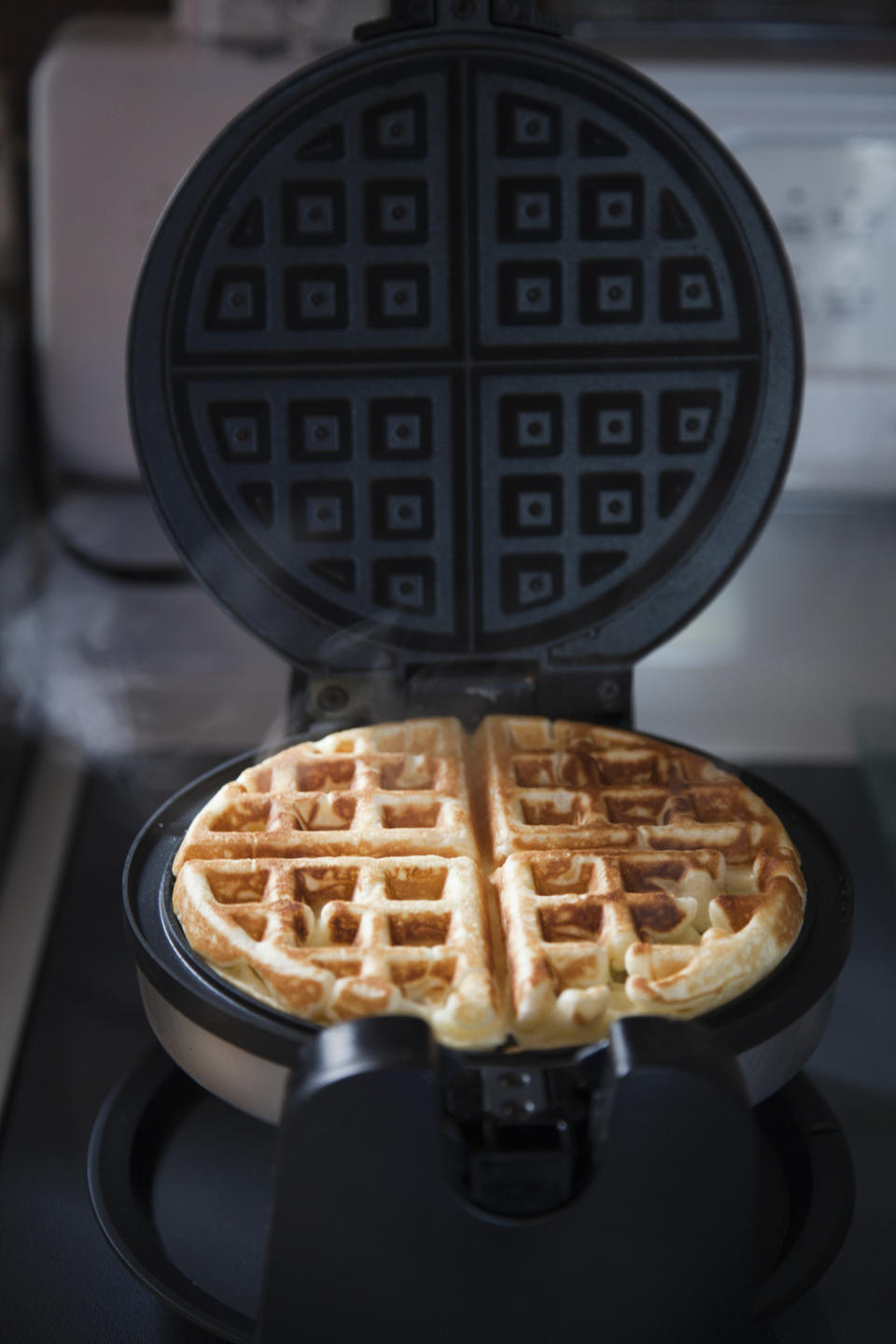 Homemade waffle baking in waffle iron.