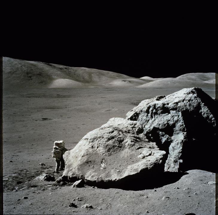 (13 Dec. 1972) — Scientist-astronaut Harrison H. Schmitt is photographed standing next to a huge, split lunar boulder during the third Apollo 17 extravehicular activity (EVA) at the Taurus-Littrow landing site. (NASA)