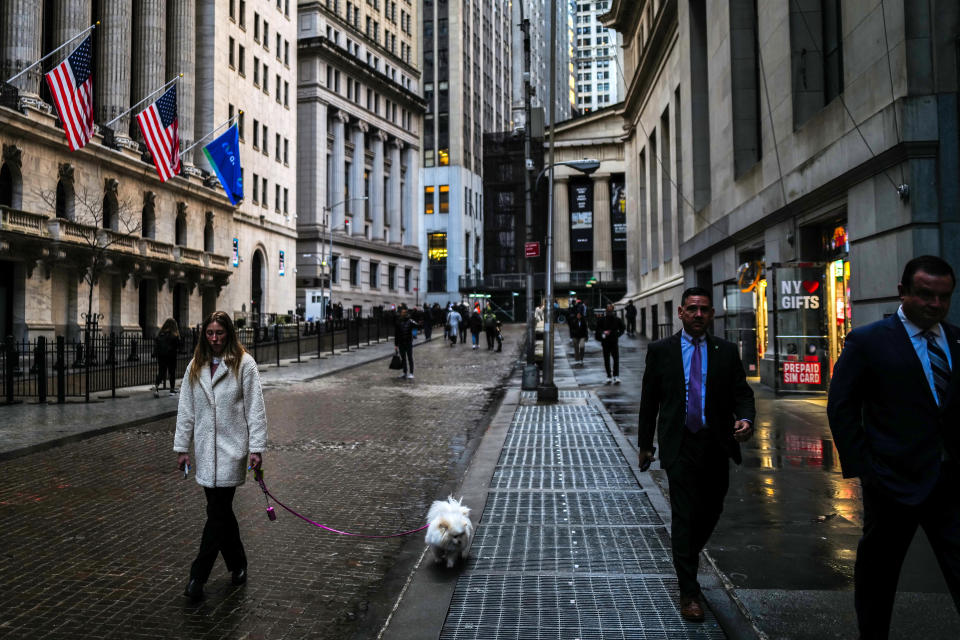 ftse A woman walks her dog past the New York Stock Exchange (NYSE) (L) at Wall Street in the Manhattan borough of New York on March 20, 2024.