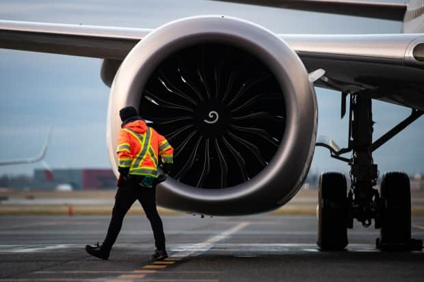 A worker walks past the engine of a Boeing 737 Max aircraft in Vancouver. Researchers say data on fly-in workers is hard to come by. Researchers say data about how may workers are in fly-in camps and what's happening within them should be publicly available. 