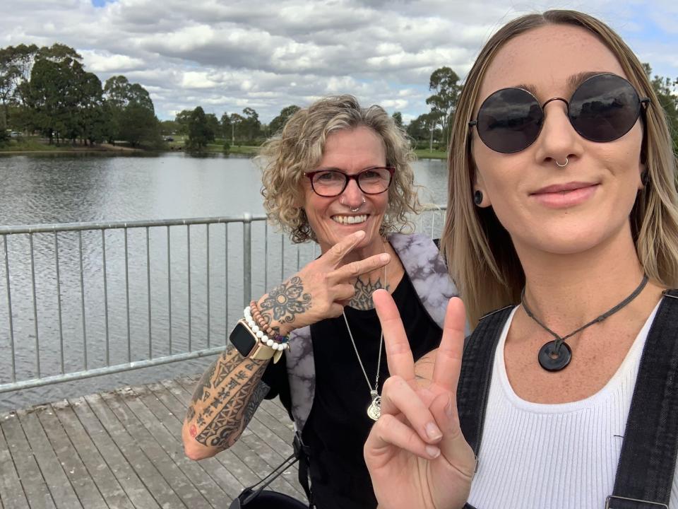 A mom and daughter flash peace signs at the camera