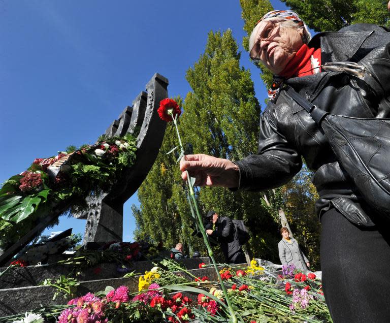 An elderly Jewish woman lays flowers in front of a monument to more than 33,000 victims of the 1941 Nazi massacre of Jews at the Babi Yar ravine in Kiev, on October 3, 2011