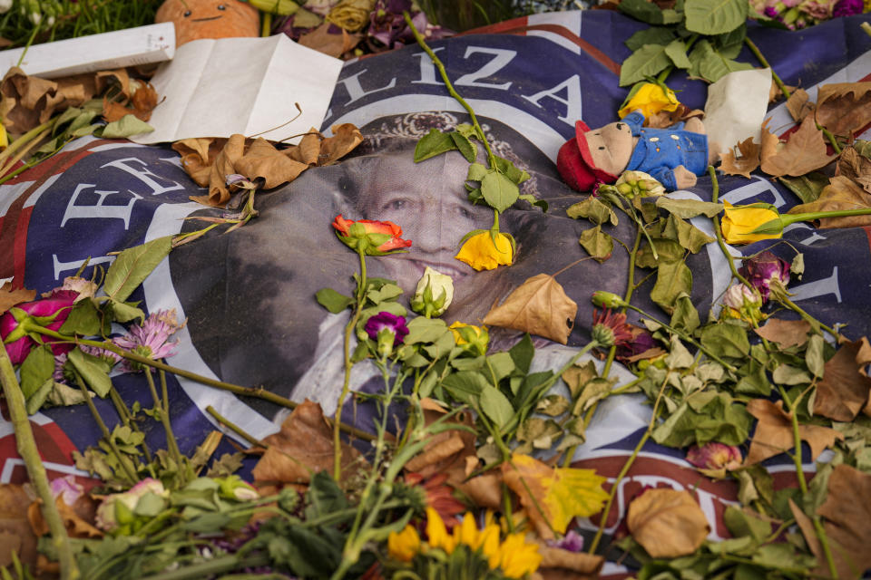 A flag carrying a portrait of Queen Elizabeth II is covered in flowers the day after her funeral, in London's Green Park, Tuesday, Sept. 20, 2022. The Queen, who died aged 96 on Sept. 8, was buried at Windsor alongside her late husband, Prince Philip, who died last year. (AP Photo/Vadim Ghirda)