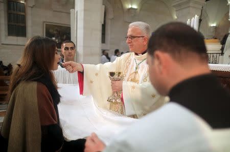 A Christian receives communion following Christmas midnight mass led by Latin Patriarch of Jerusalem Fouad Twal at the Church of the Nativity in the West Bank town of Bethlehem December 25, 2015. REUTERS/Fadi Arouri/Pool