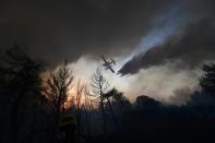 An aircraft drops water during a wildfire in Kryoneri area, northern Athens, Greece, Thursday, Aug. 5, 2021. Wildfires rekindled outside Athens and forced more evacuations around southern Greece Thursday as weather conditions worsened and firefighters in a round-the-clock battle stopped the flames just outside the birthplace of the ancient Olympics. (AP Photo/Michael Varaklas)