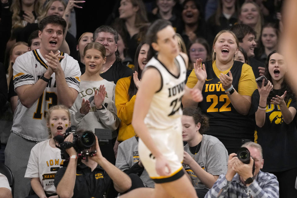 Fans applaud Iowa guard Caitlin Clark (22) after she broke the NCAA women's career scoring record during the first half of the team's college basketball game against Michigan on Thursday, Feb. 15, 2024, in Iowa City, Iowa. (AP Photo/Matthew Putney)