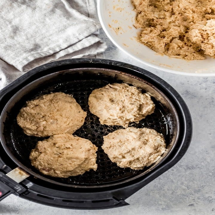 Tuna patties in the basket of an air fryer.