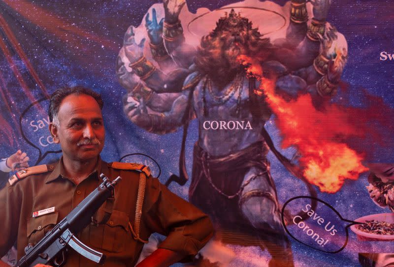 A policeman stands guard next to a caricature as members of All India Hindu Mahasabha attend a gaumutra (cow urine) party, which according to them helps in warding off coronavirus disease (COVID-19), in New Delhi