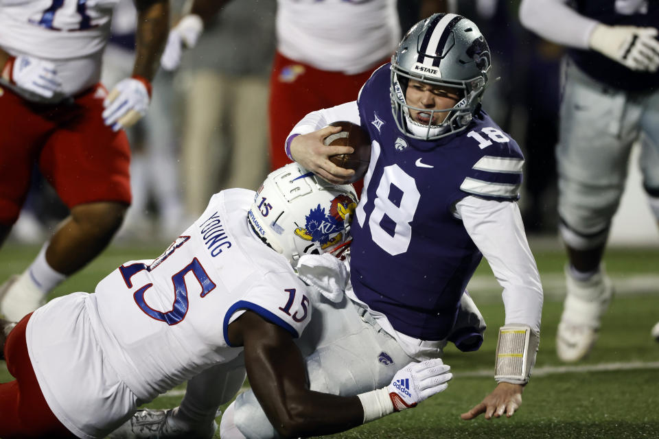 Kansas State quarterback Will Howard (18) is tackled by Kansas linebacker Craig Young (15) after scrambling for a first down during the first quarter of an NCAA college football game Saturday, Nov. 26, 2022, in Manhattan, Kan. (AP Photo/Colin E. Braley)