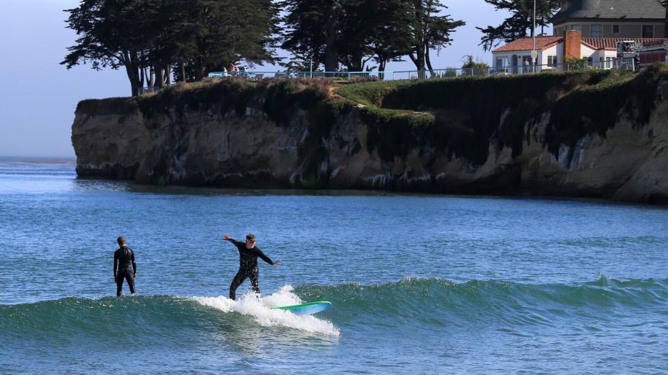 A man surfs while someone else watches