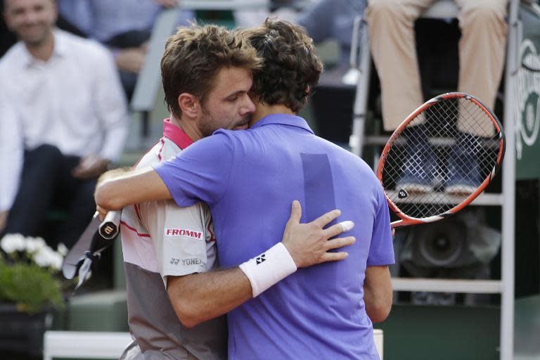 Switzerland's Stanislas Wawrinka (L) embraces Switzerland's Roger Federer at the end of their men's quarter final match of the Roland Garros 2015 French Tennis Open in Paris on June 2, 2015