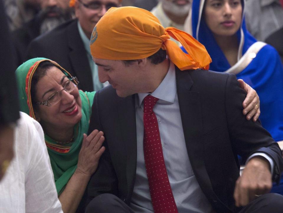 A woman embraces Prime Minister Justin Trudeau as he sits on the floor beside her at the start of a Vaisakhi Celebration on Parliament Hill in Ottawa, Monday April 11, 2016. THE CANADIAN PRESS/Adrian Wyld