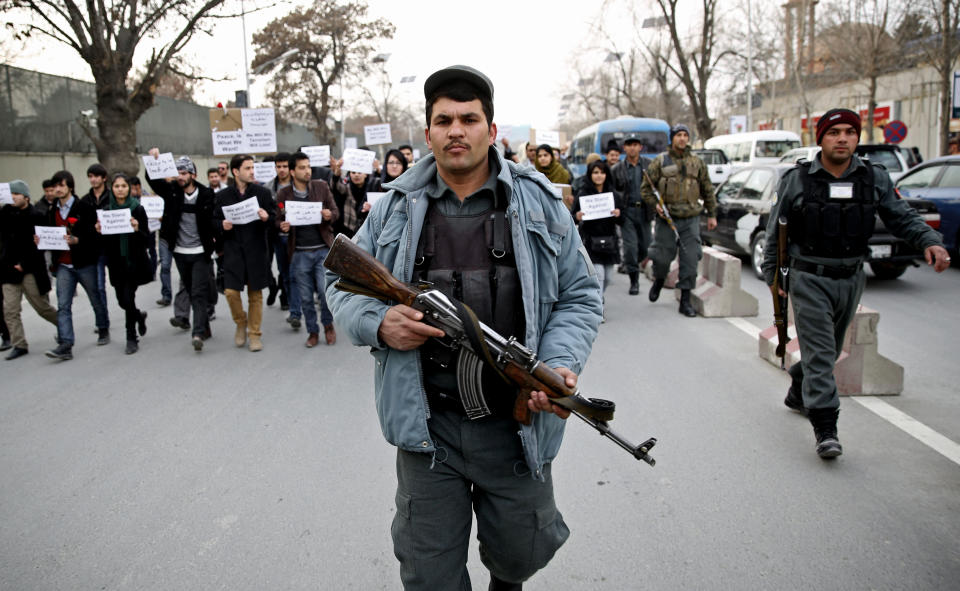 An Afghan police walks ahead of members of civil society organizations for their protection as they march in a street, during an anti terrorism demonstration in Kabul, Afghanistan, Sunday, Jan. 19, 2014. Hundreds of Afghans gathered outside a Lebanese restaurant in Kabul on Sunday to protest against Taliban attack that killed 21 people. The assault Friday by a Taliban bomber and two gunmen against the La Taverna du Liban restaurant was deadliest single attack against foreign civilians in the course of a nearly 13-year U.S.-led war there now approaching its end. They chanted slogans against terrorism as they laid flowers at the site of the attack. The dead included 13 foreigners and eight Afghans, all civilians. The attack came as security has been deteriorating and apprehension has been growing among Afghans over their country's future as U.S.-led foreign forces prepare for a final withdrawal at the end of the year. (AP Photo/Massoud Hossaini)