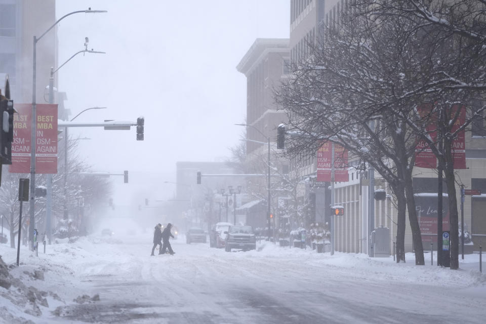 Pedestrians cross the street in snowy conditions Friday, Jan. 12, 2024, in Des Moines, Iowa. (AP Photo/Abbie Parr)