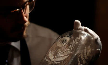 A member of Sotheby's staff poses for a photograph with a decanter from the "Grog Chest" which forms part of a sale of items called Nelson's Legend, in London, Britain January 11, 2018. REUTERS/Peter Nicholls